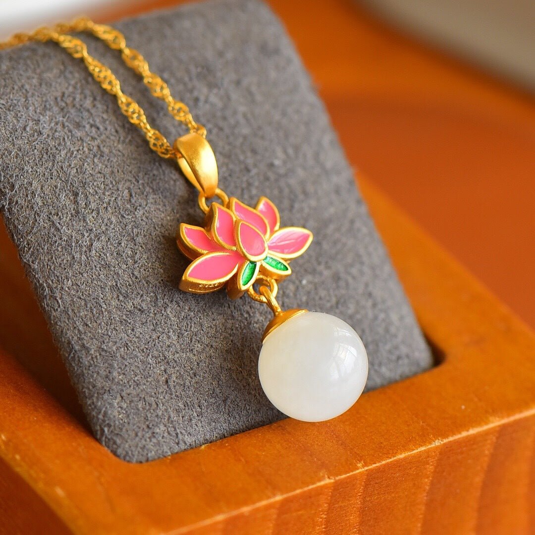 Lotus keepsake necklace displayed on velvet – white jade and warm gold glowing under soft light
