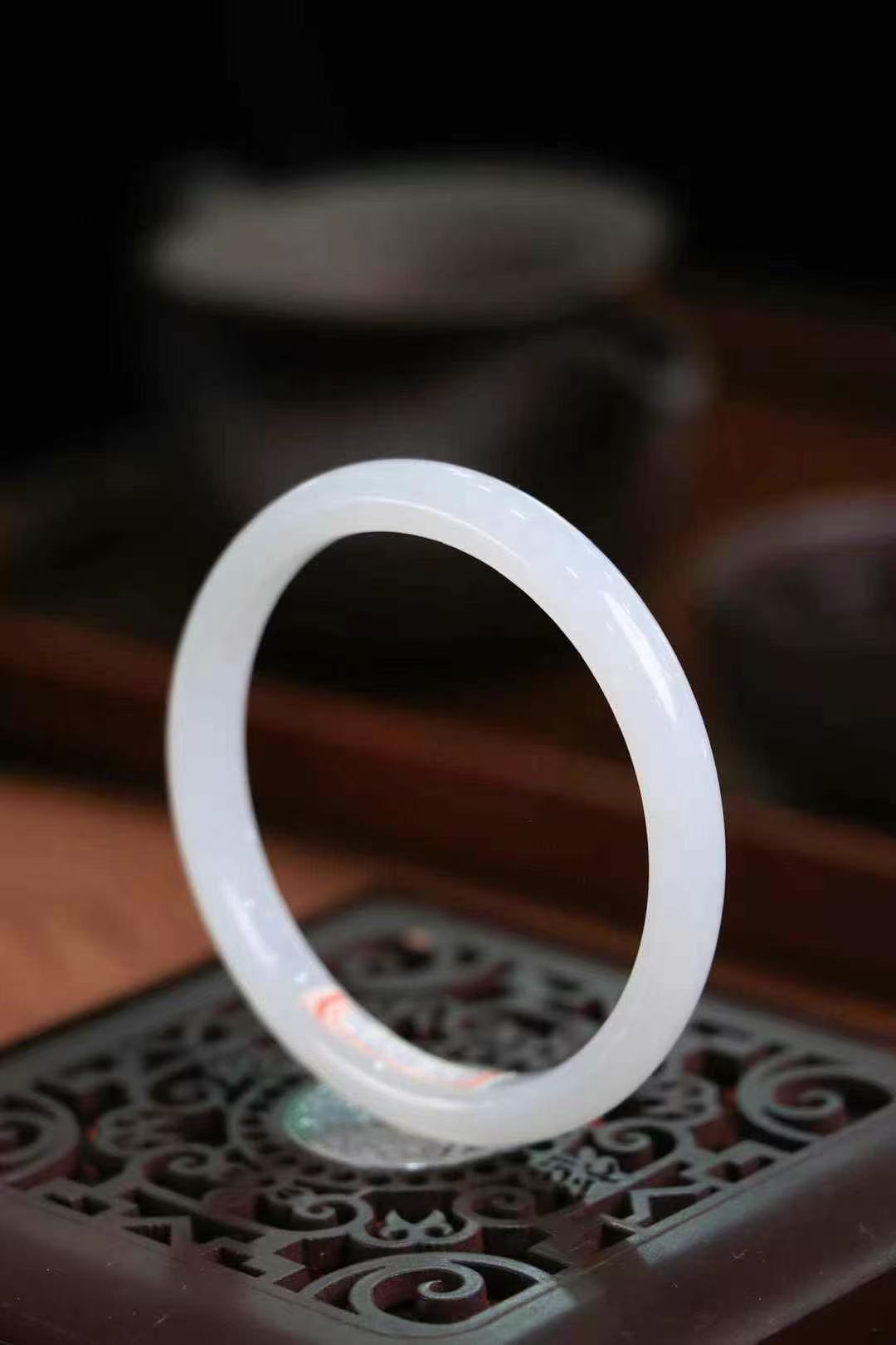 Close-up of a smooth white jade bangle, catching soft light in a quiet moment