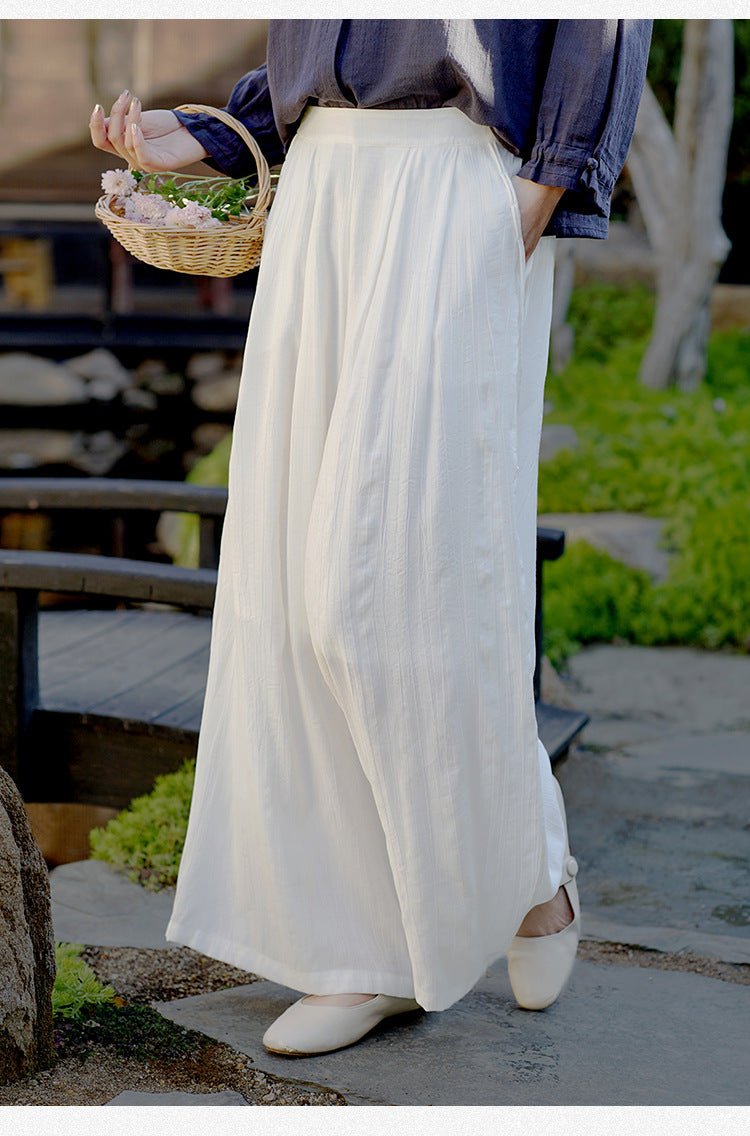 Side view of white wide-leg pants in motion – flowing fabric catching breeze in garden path
