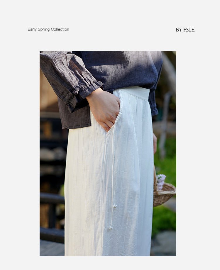 Soft wide-leg pants in natural linen, worn with ease – model walking outdoors in layered styling