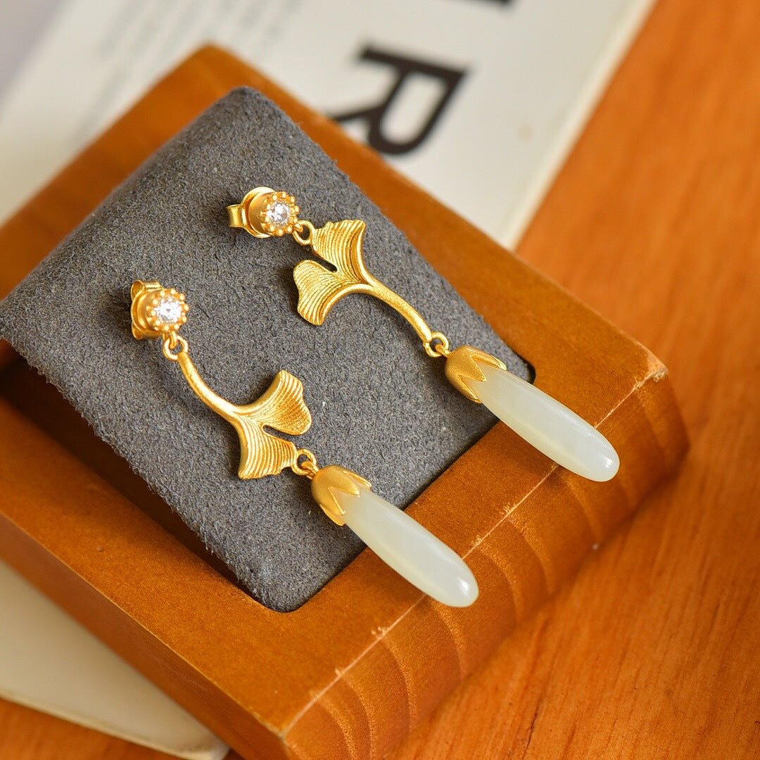 Delicate ginkgo leaf earrings resting on soft grey velvet – gold and jade in quiet harmony