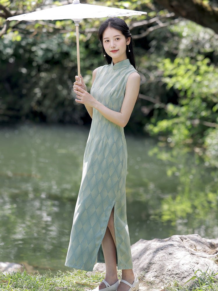Elegant woman standing under sunlight in a vintage-style green qipao with floral patterns.