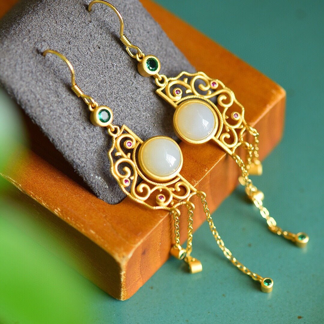 Pair of long jade tassel earrings resting on folded fabric – soft textures and quiet elegance
