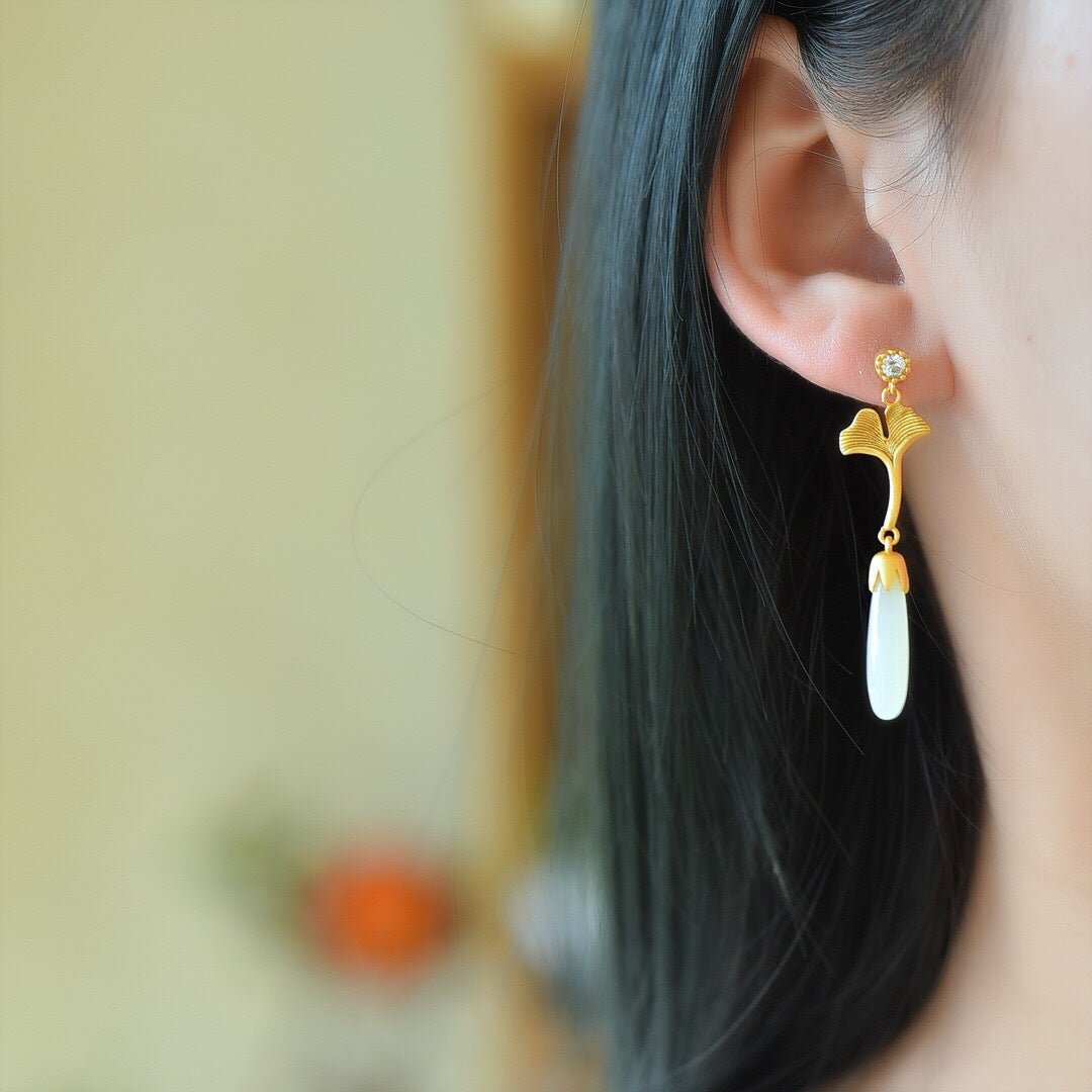 Model wearing white jade drop earrings with gold ginkgo leaves – soft side profile, elegant movement