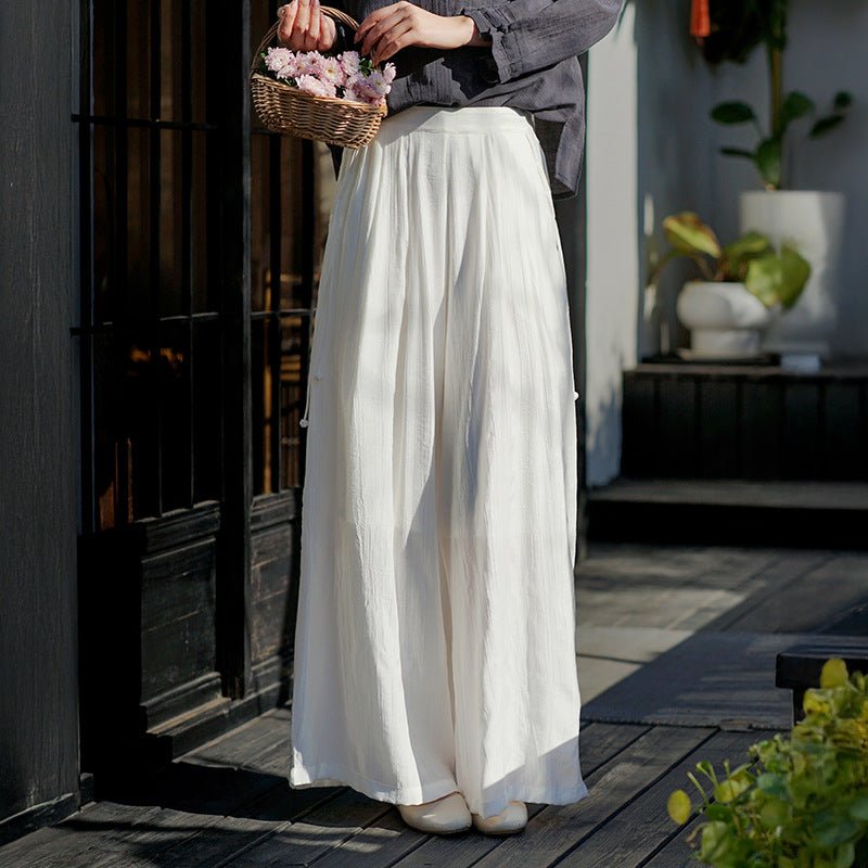 Wide-leg linen pants with side ties flowing gently as model walks past a tea house entrance – soft movement