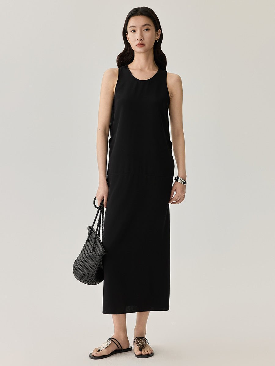Full-body view of a woman in a simple black slip dress and heels, standing confidently.