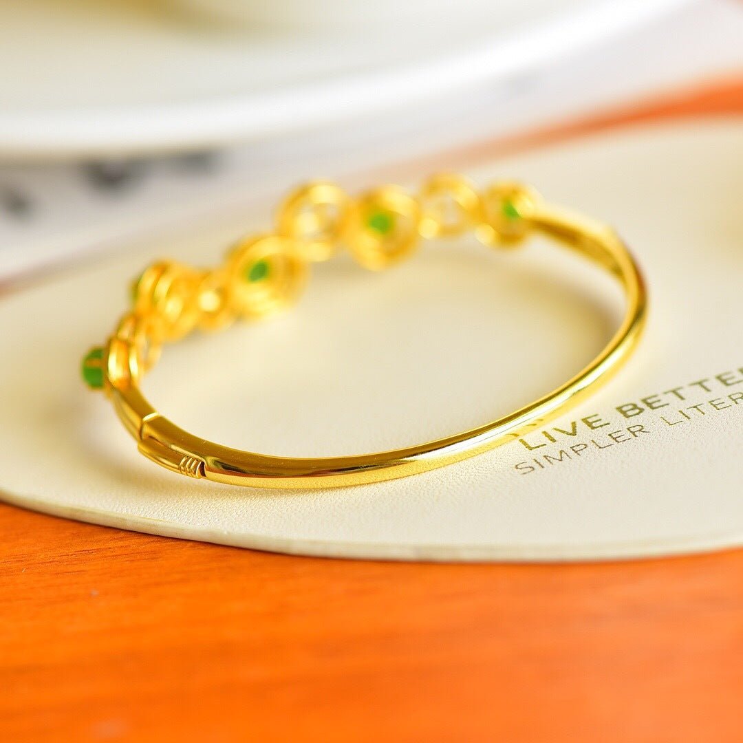 Elegant gold bangle featuring polished green jade beads and floral engraving details.