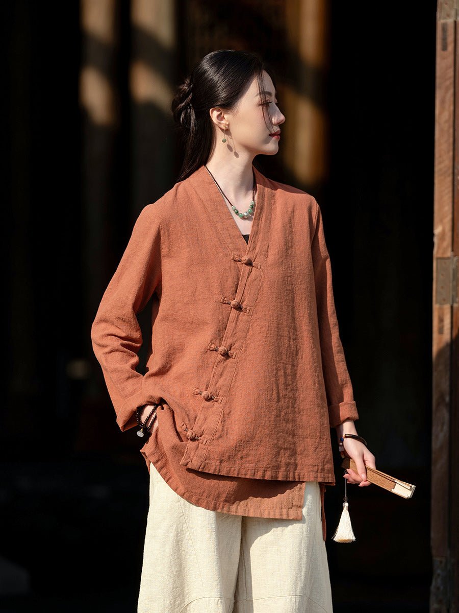 Elegant woman in a terracotta cotton-linen top with delicate embroidery, hands in pocket, bathed in warm evening light.