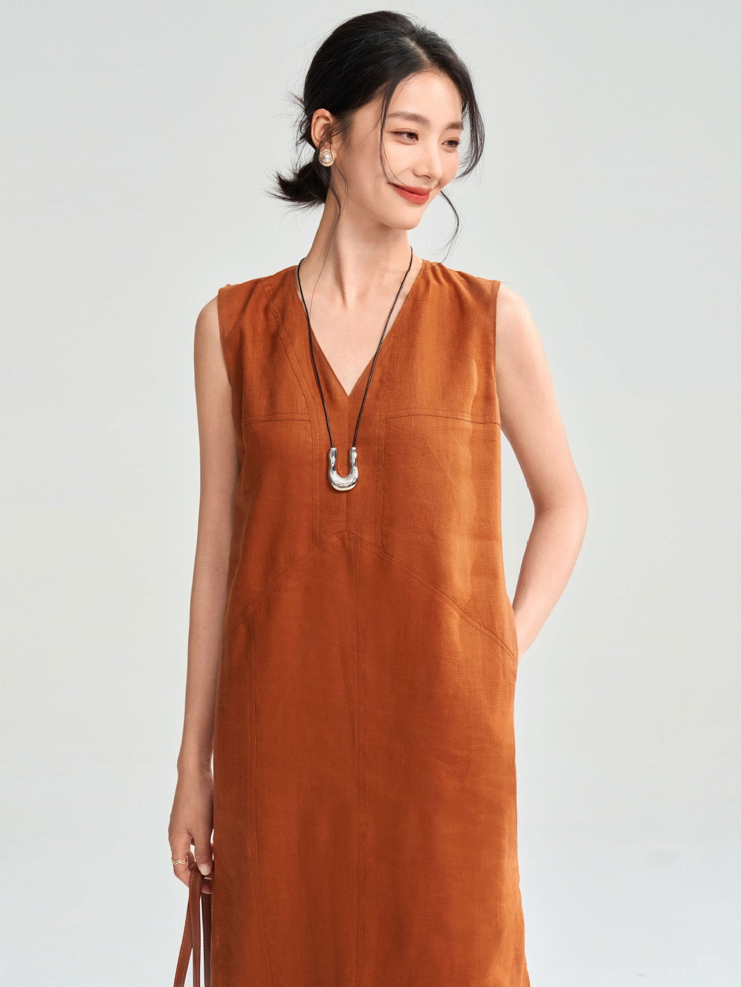 Woman in rust-colored sleeveless dress – soft linen texture, calm expression