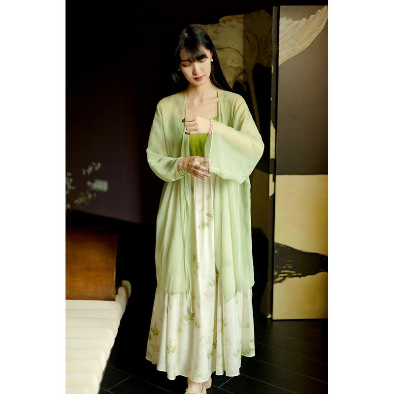 Woman in a light green Hanfu with long sleeves, standing calmly in soft indoor light.