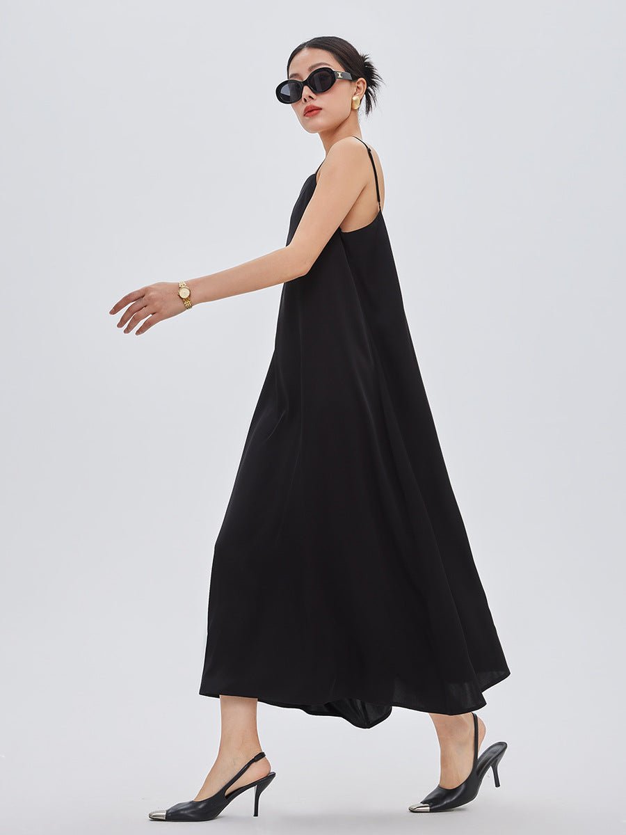 Woman in a black spaghetti strap maxi dress and heels, captured mid-walk with a graceful flair.
