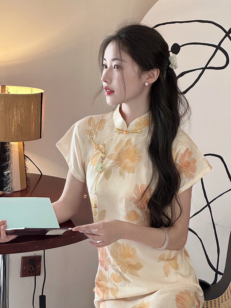Young woman in a buttery yellow jacquard qipao holding a teacup in a cozy, vintage-style room.