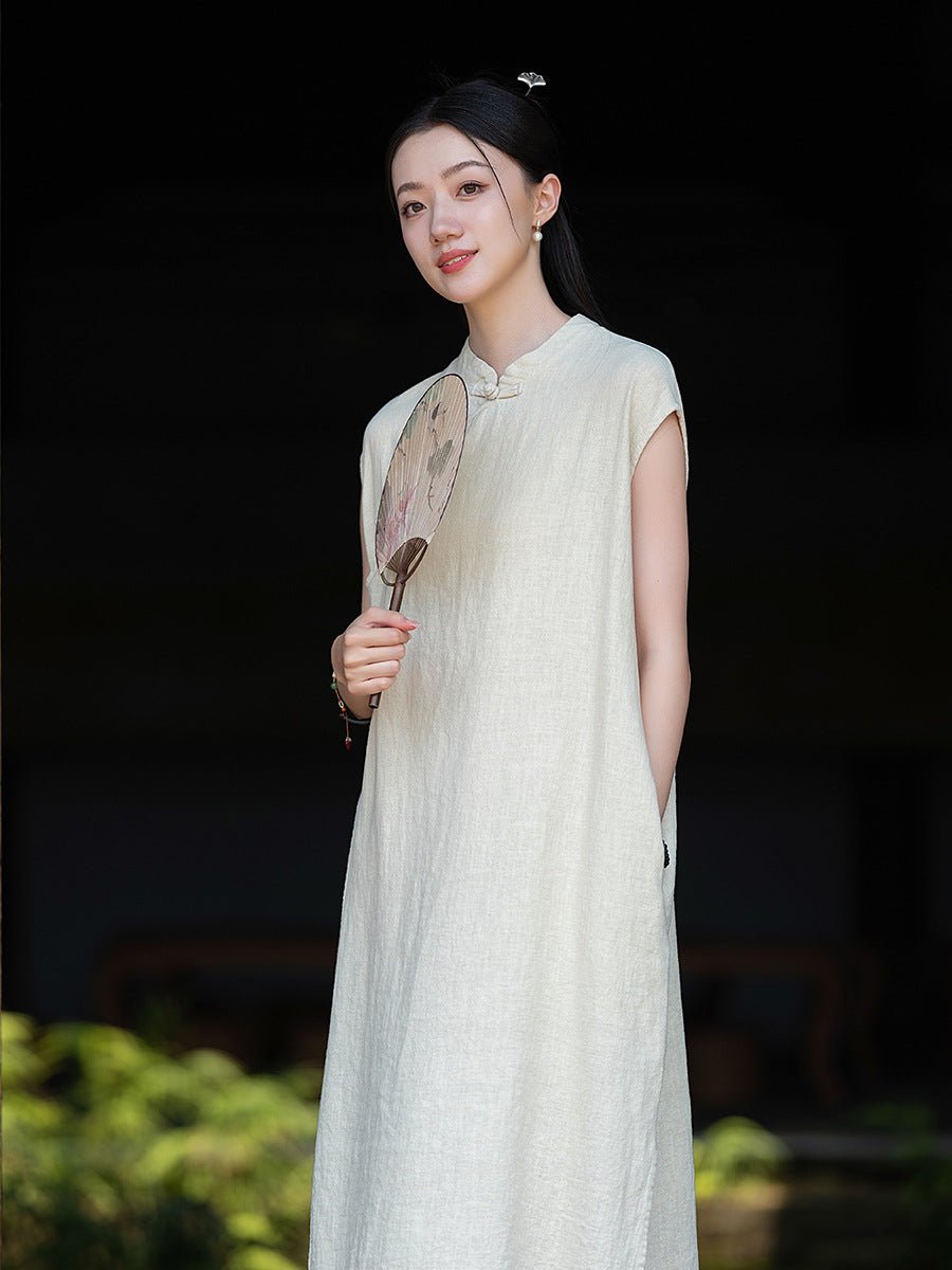Woman wearing a sleeveless white linen dress, standing gracefully outdoors at night.