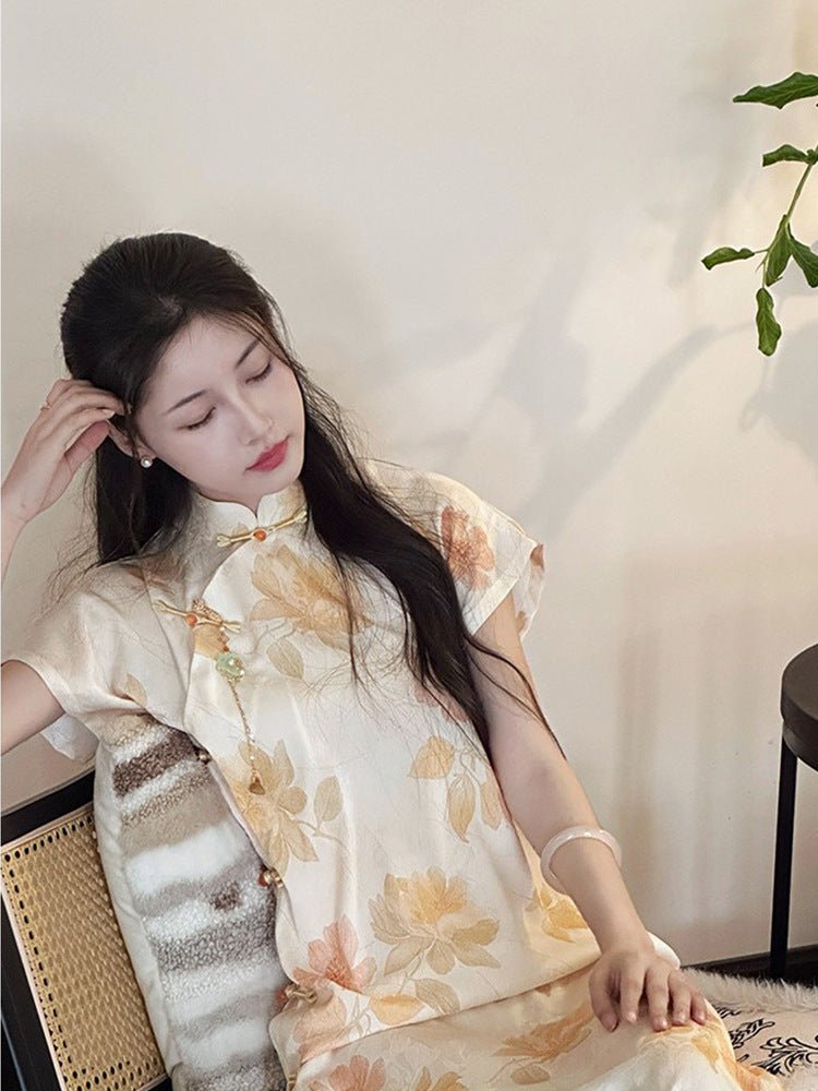 Elegant girl in a light golden floral cheongsam reclining on a chair, with soft lighting and indoor plants.