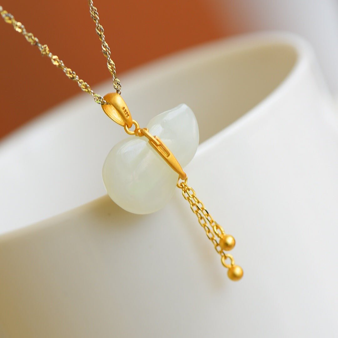 Elegant gold-thread necklace with Hetian jade charm – softly lit on a pale curved surface