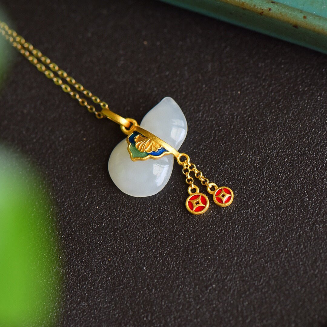 White jade gourd pendant with small amber charm on black background.